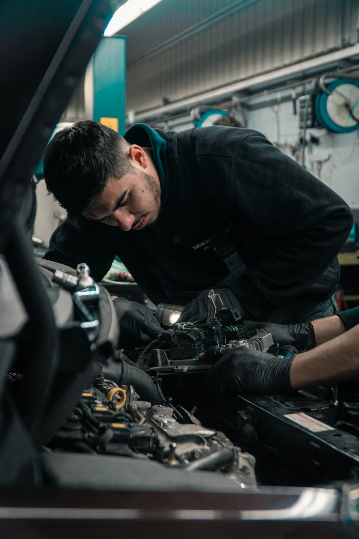 A professional mechanic inspecting a vehicle's undercarriage and exhaust system on a hoist